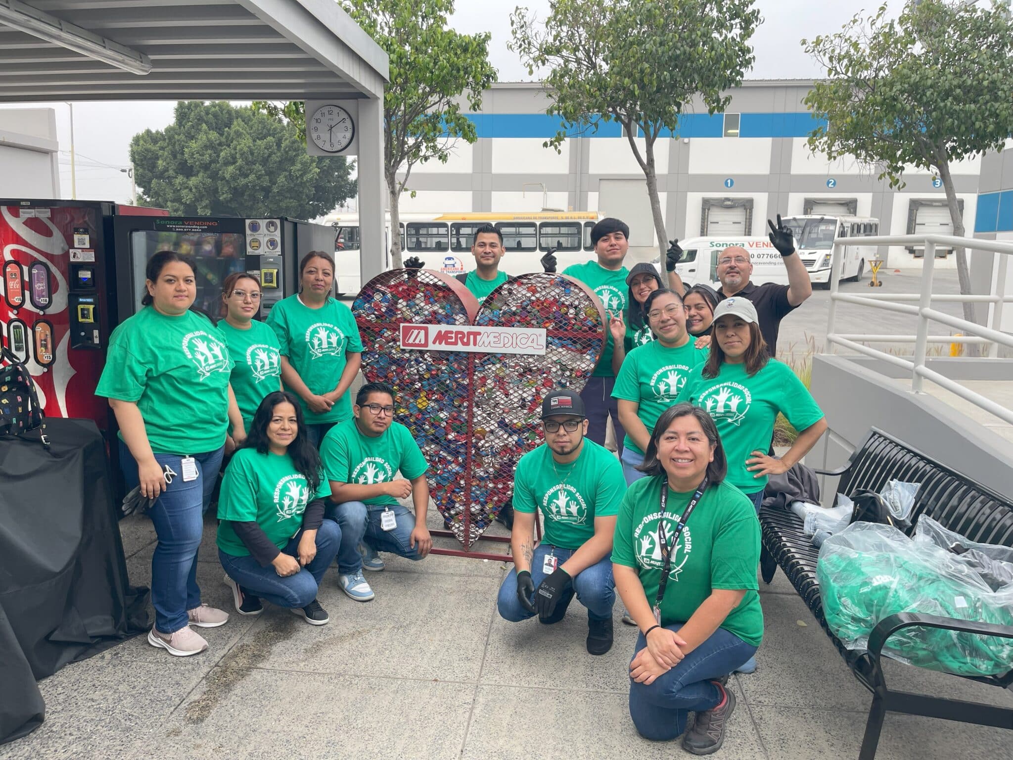 Merit Tijuana employees gathered around the HEART-shaped recycle bin